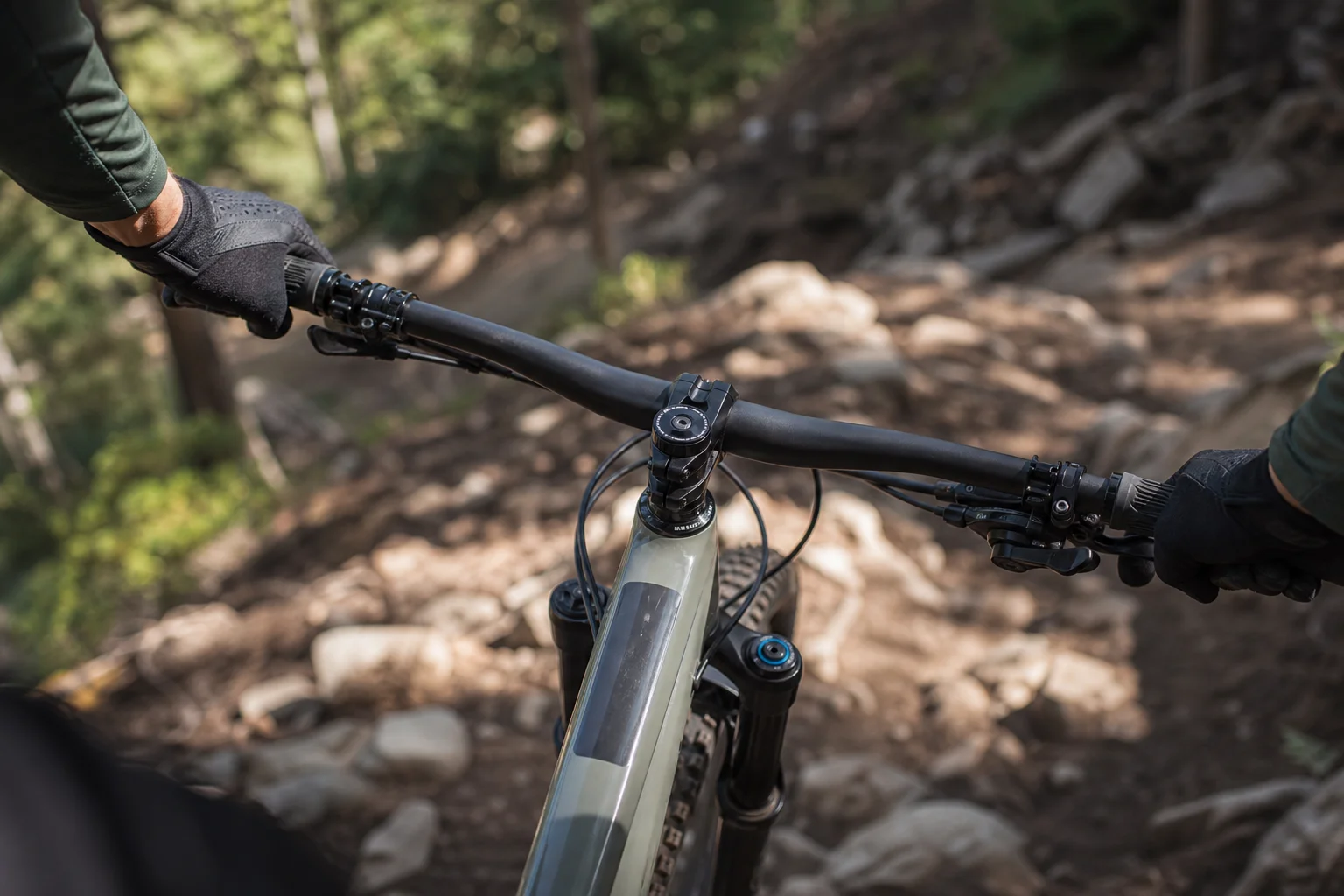 Mountain biker gripping handlebars on a rocky trail descent