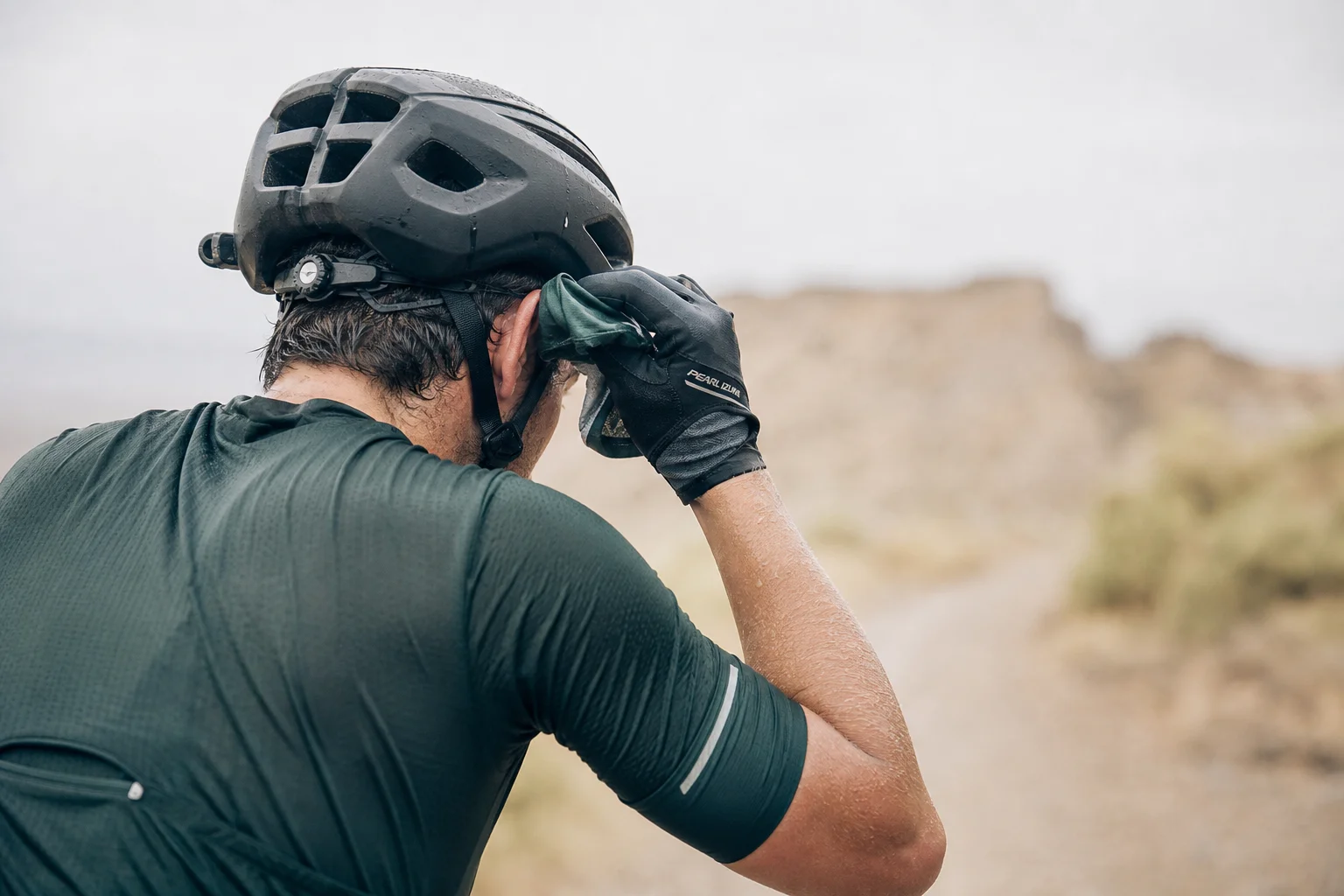 Cyclist wiping sweat from forehead with gloved hand during a ride