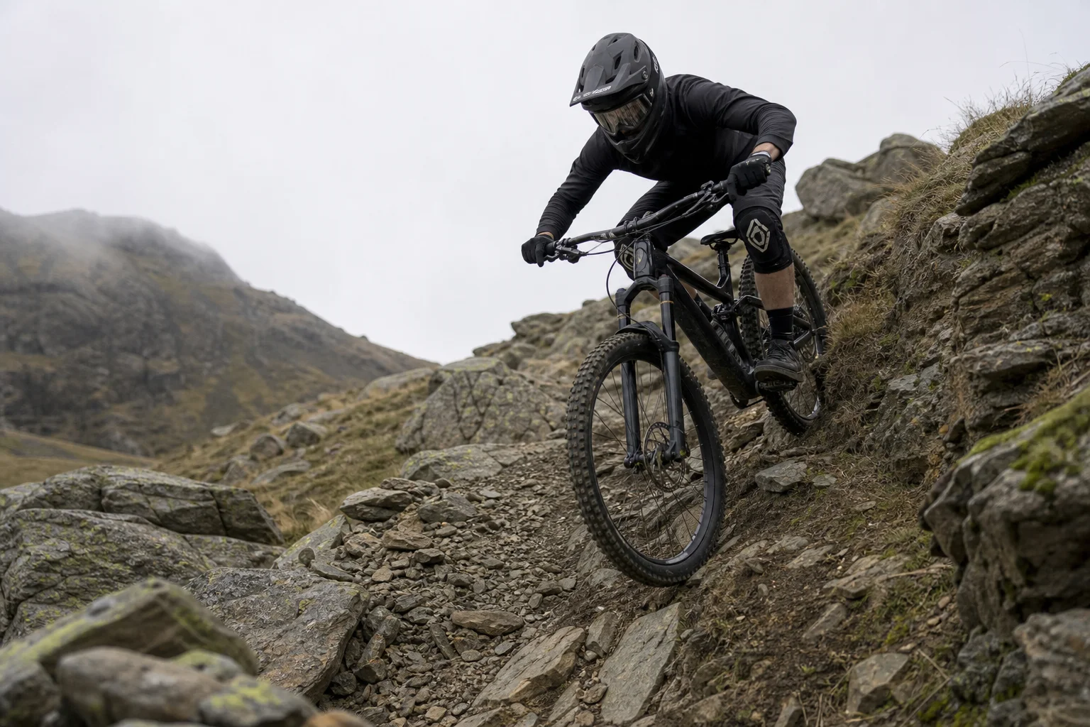 Mountainbiker bei der Abfahrt in steilem, felsigem Gelände mit Schutzausrüstung