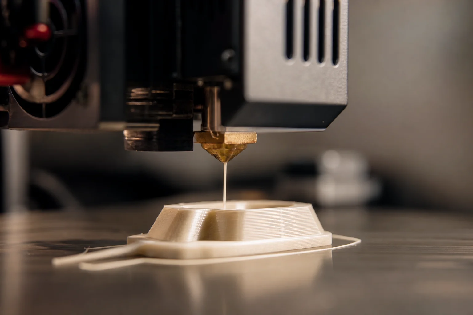 Nahaufnahme einer 3D-Druckerdüse, die Filament auf das Druckbett extrudiert