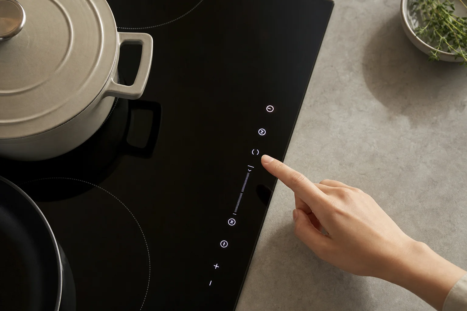 Main ajustant les commandes tactiles sur l'écran d'une plaque à induction moderne