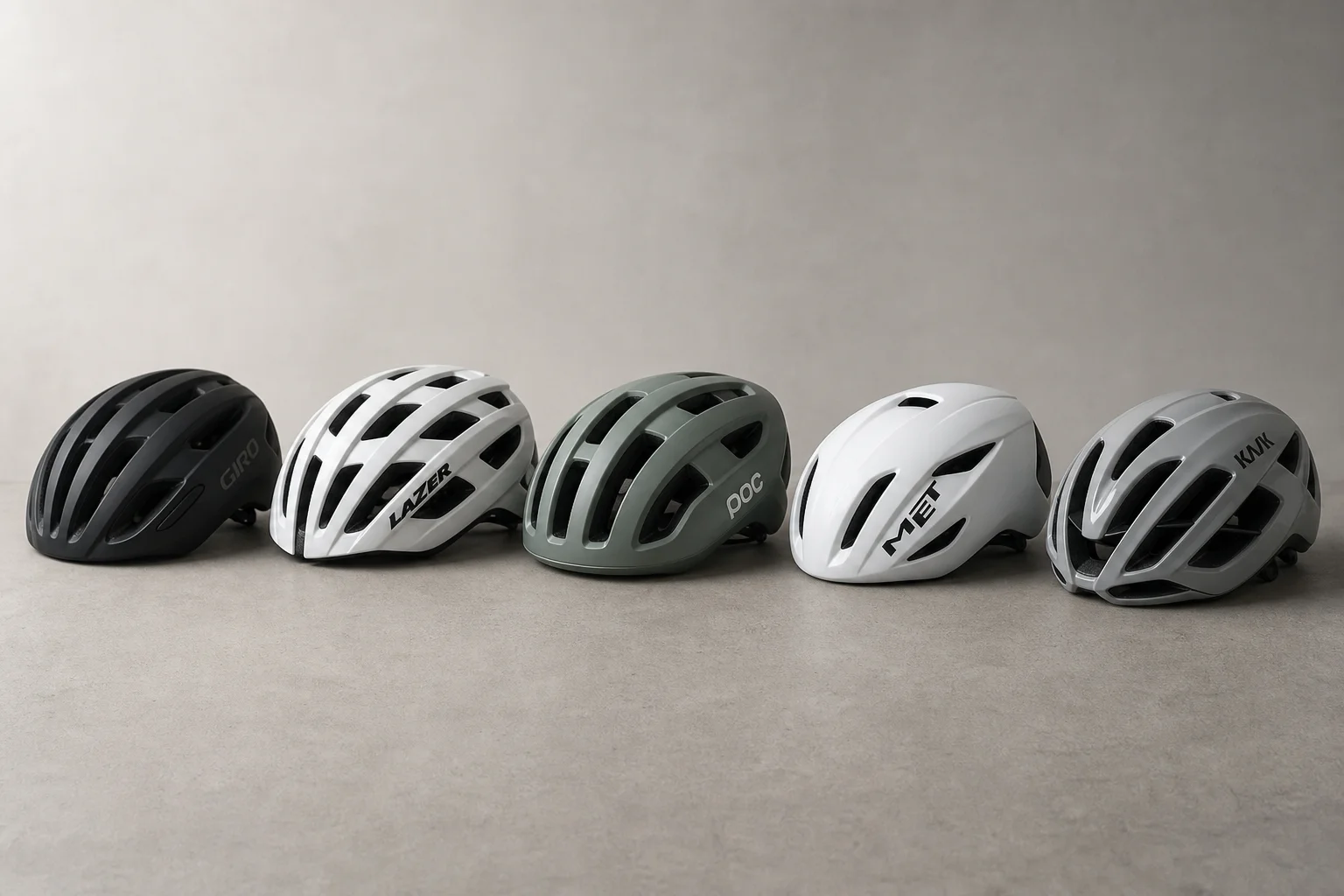 Five road bike helmets arranged in a row on concrete surface showing different designs