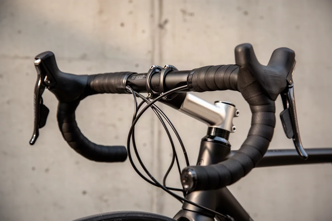 Primer plano del manillar de una bicicleta de carretera con cables de freno y cambio expuestos