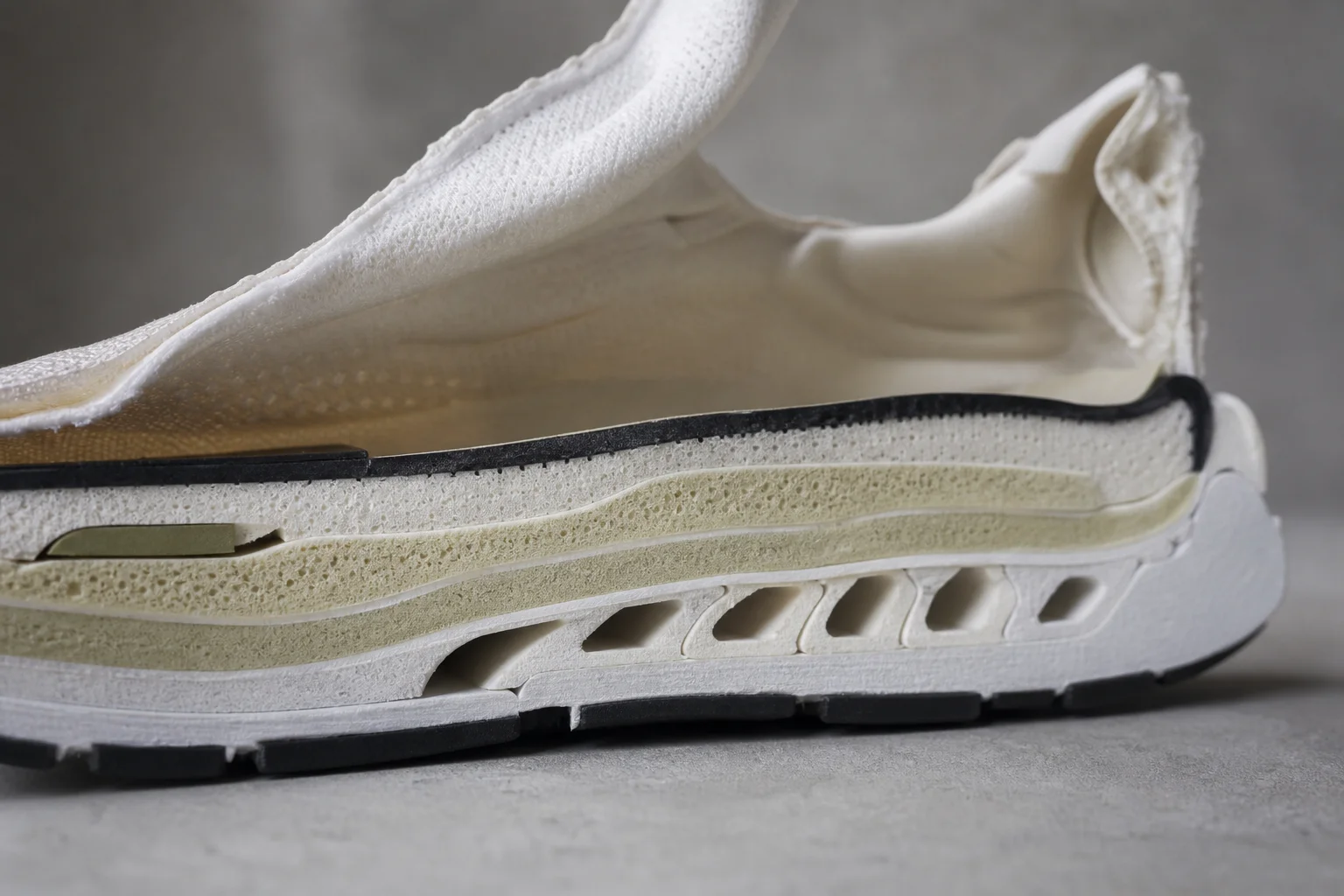 Primer plano de la entresuela y el material de amortiguación de una zapatilla de running en sección transversal