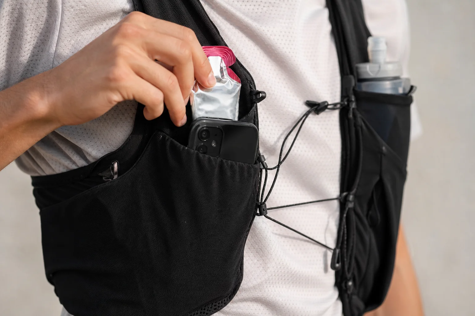 Primo piano delle tasche frontali di un gilet da running con gel e spazio per lo smartphone