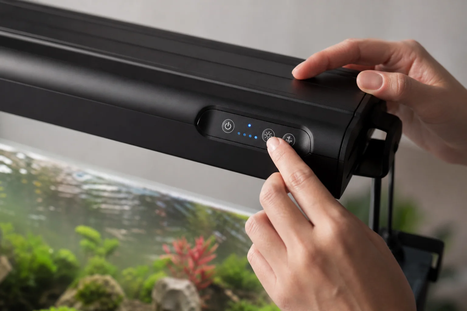 Mains ajustant les commandes d'une rampe d'éclairage d'aquarium dimmable