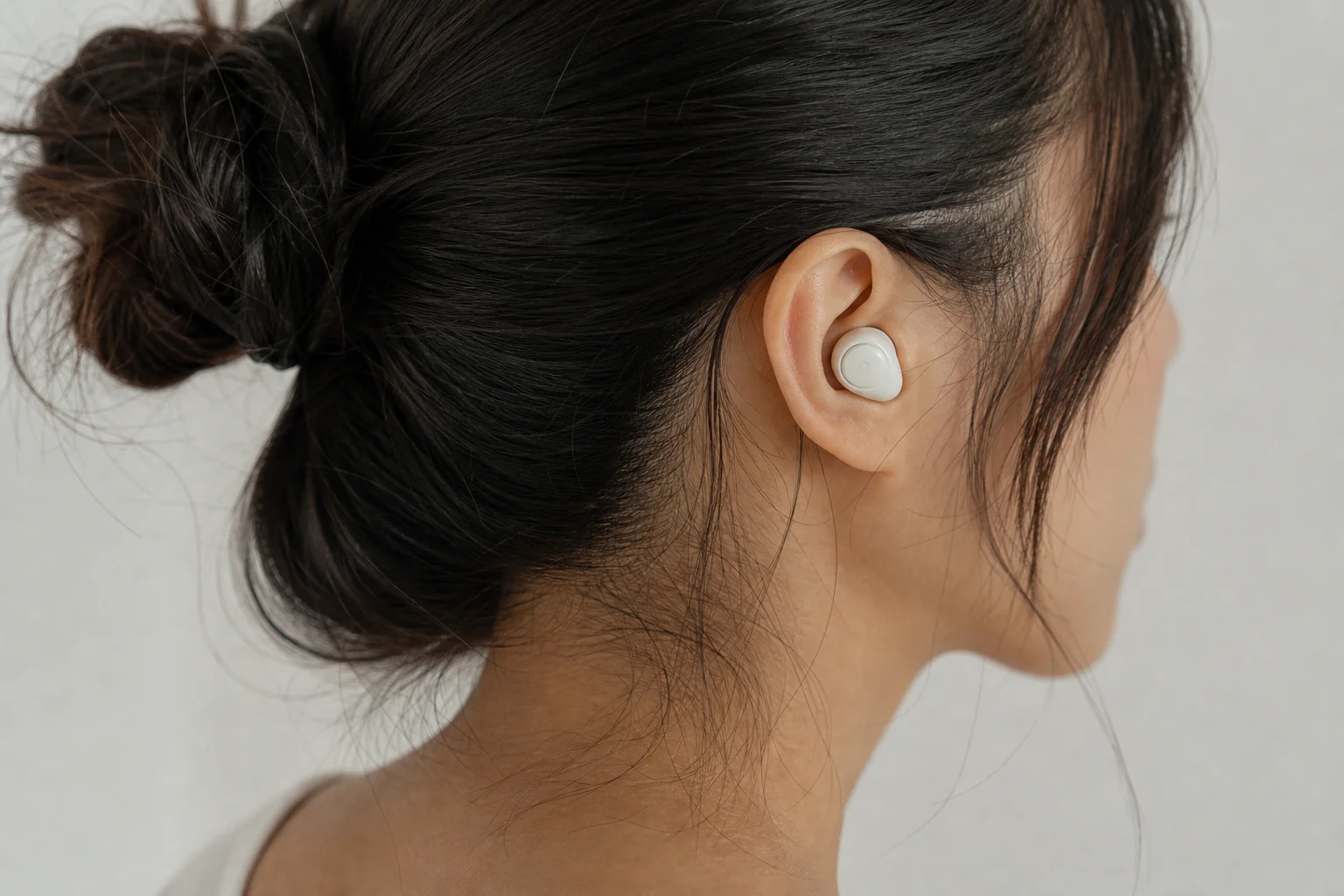 Persona usando auriculares en un entorno de escucha con un fondo neutro