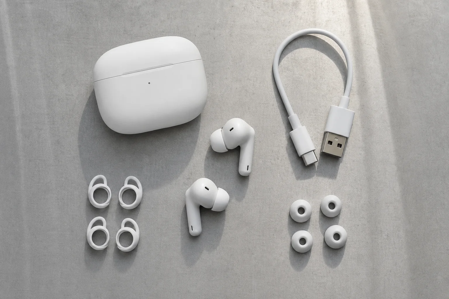 Estuche de carga de auriculares y accesorios dispuestos sobre una superficie minimalista