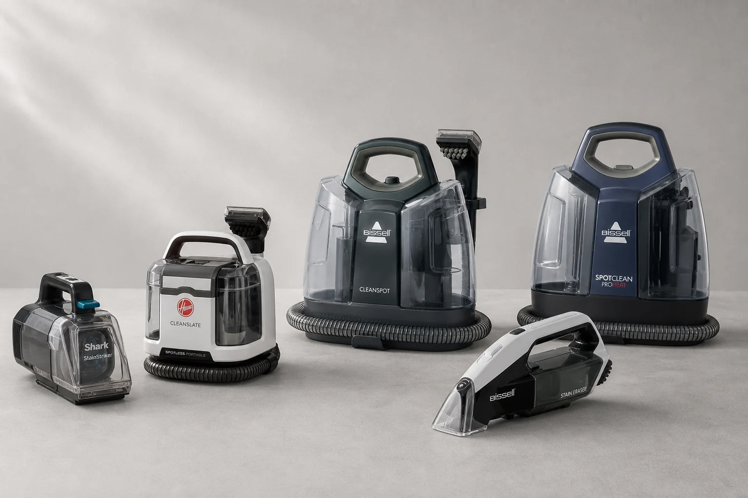 Multiple portable spot cleaners arranged on neutral surface showing variety of models