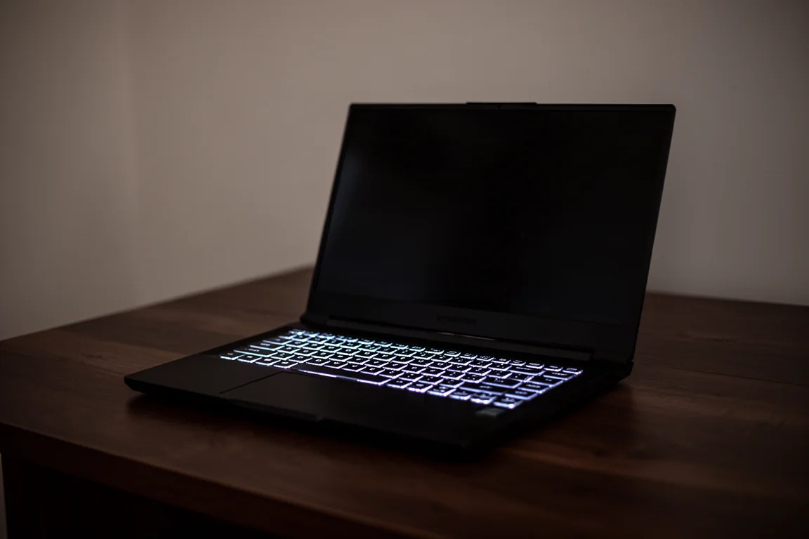 Gaminglaptop öppen på ett skrivbord med svag skärmglöd i ett mörkt rum