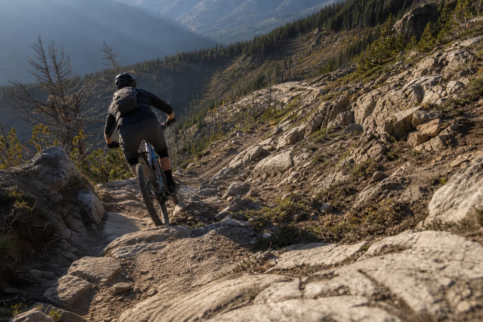 Mountain biker che scende lungo un sentiero roccioso ripido con passaggi tecnici