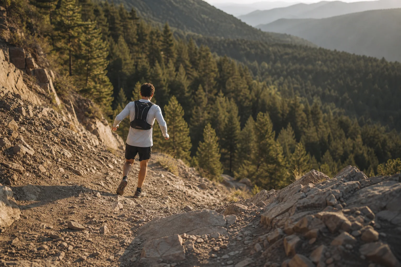 Trailrunner bei einem felsigen Abstieg mit bewaldetem Hang im Hintergrund