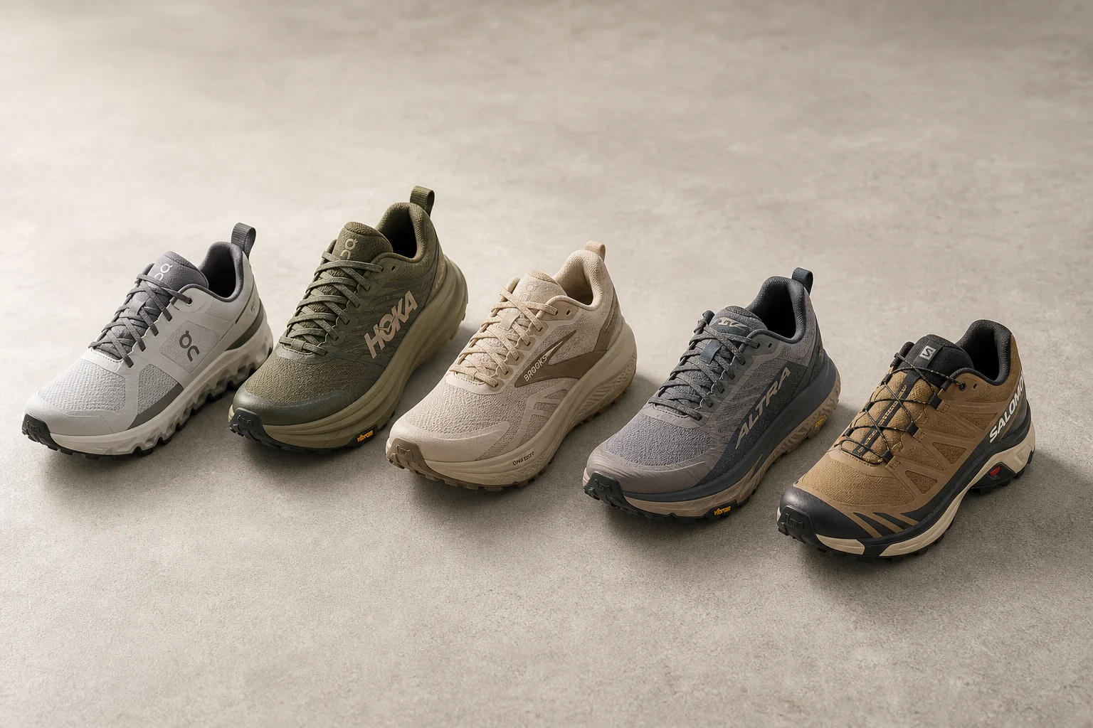 五款越野跑鞋排列在水泥地面上，展示出不同的設計風格