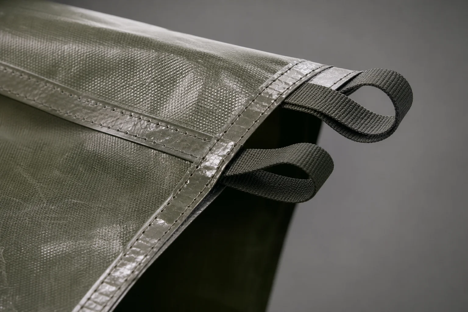 Close-up of tarp fabric showing reinforced webbing loops and stitching detail