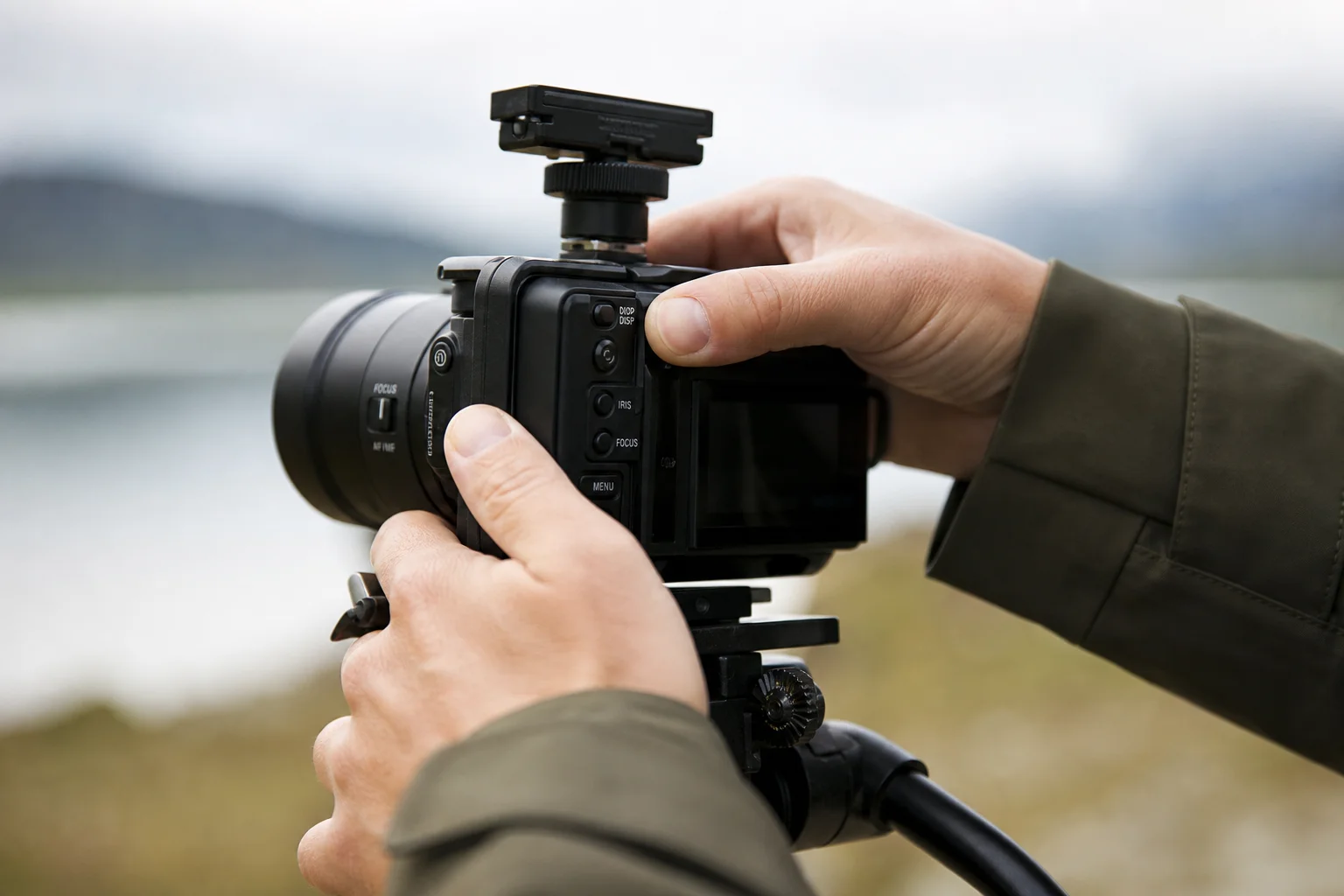 Händer justerar inställningar på en videokamera under utomhusinspelning