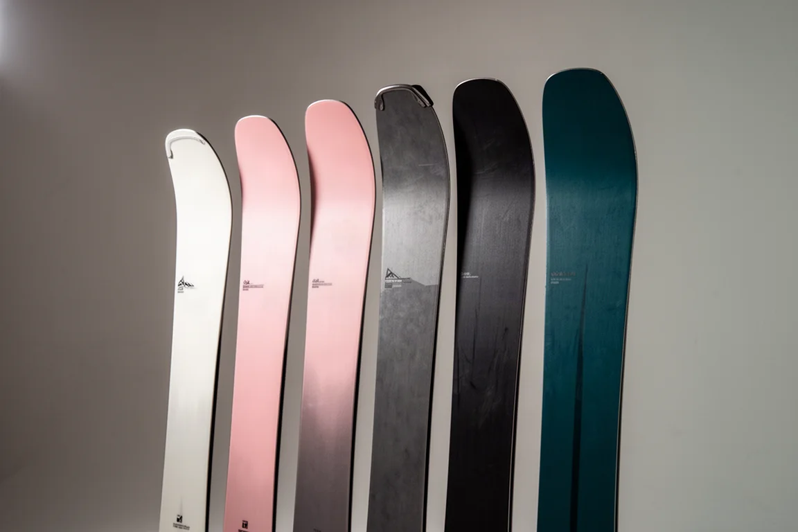 Row of wide freeride skis standing upright on a neutral grey backdrop