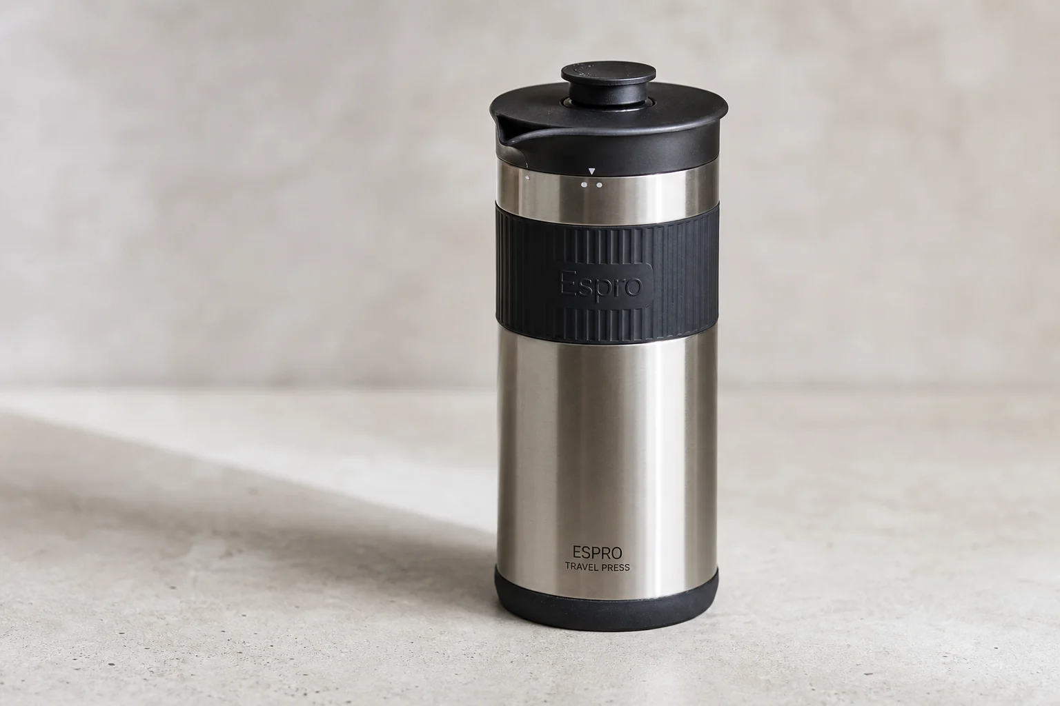 Five portable coffee makers arranged on concrete: Zyliss mug, Coffee Gator travel mug, Espro press, Bodum French press, and AeroPress Go