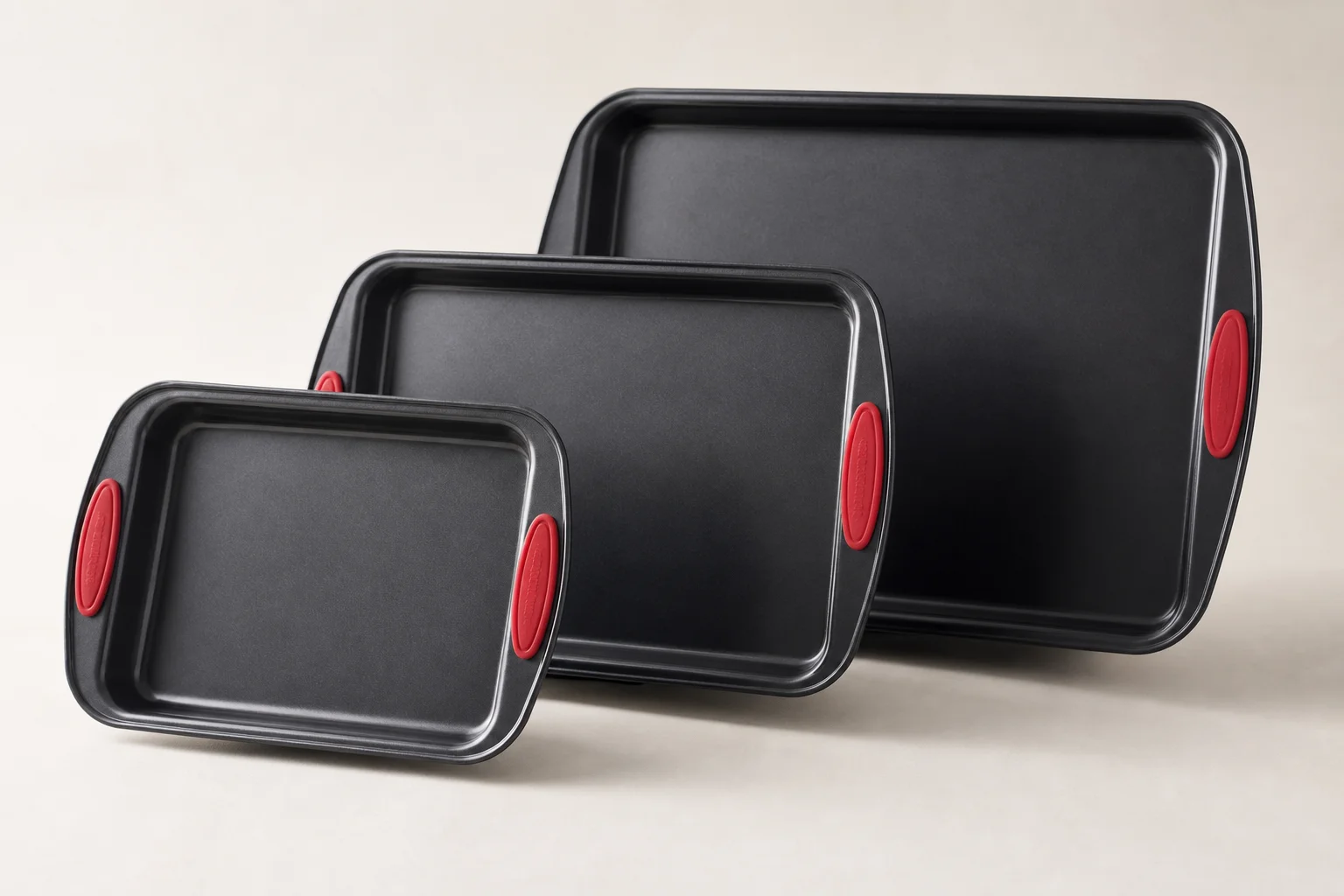 Five different baking sheets and pans arranged on a concrete surface