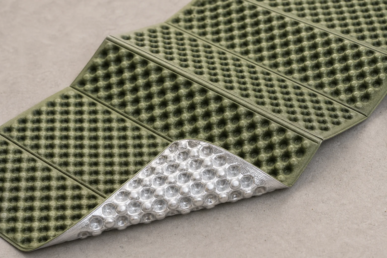 Close-up of a foldable foam sleeping mat showing the egg-tray pattern and aluminium foil backing