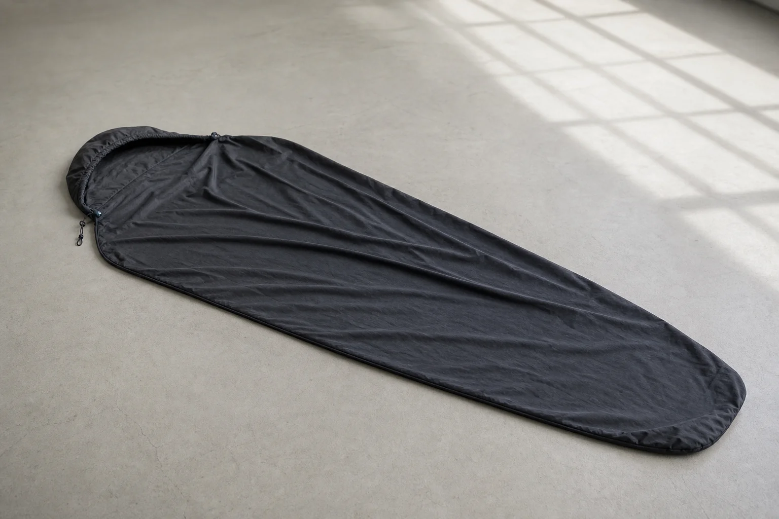 Sleeping bag liner stretched out showing the soft fabric texture and draw cord hood