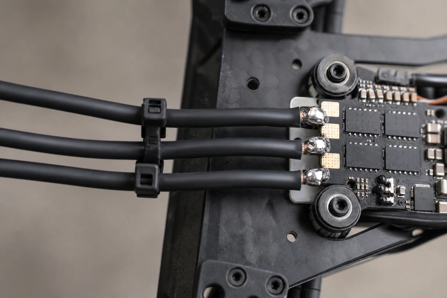 Fios dos motores soldados aos pads do ESC e fixados com abraçadeiras no braço