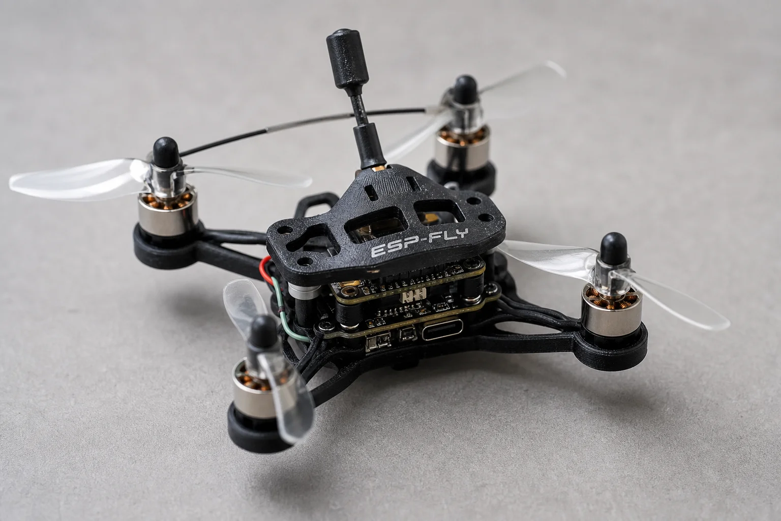 Micro drone ESP-FLY assemblato su una superficie grigia che mostra il design compatto del quadricottero