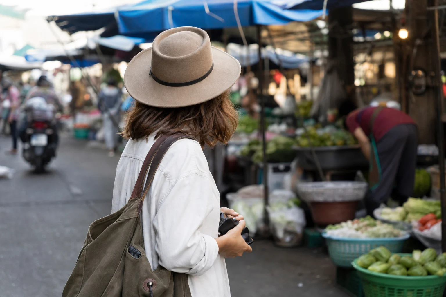 Street photographer holding compact camera at waist level in urban market setting