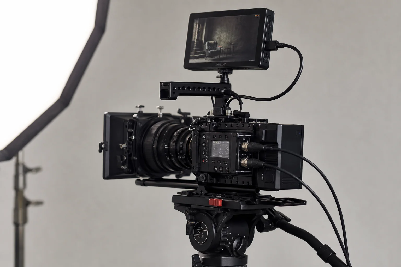 Cinema camera mounted on tripod with external monitor and XLR audio connectors visible