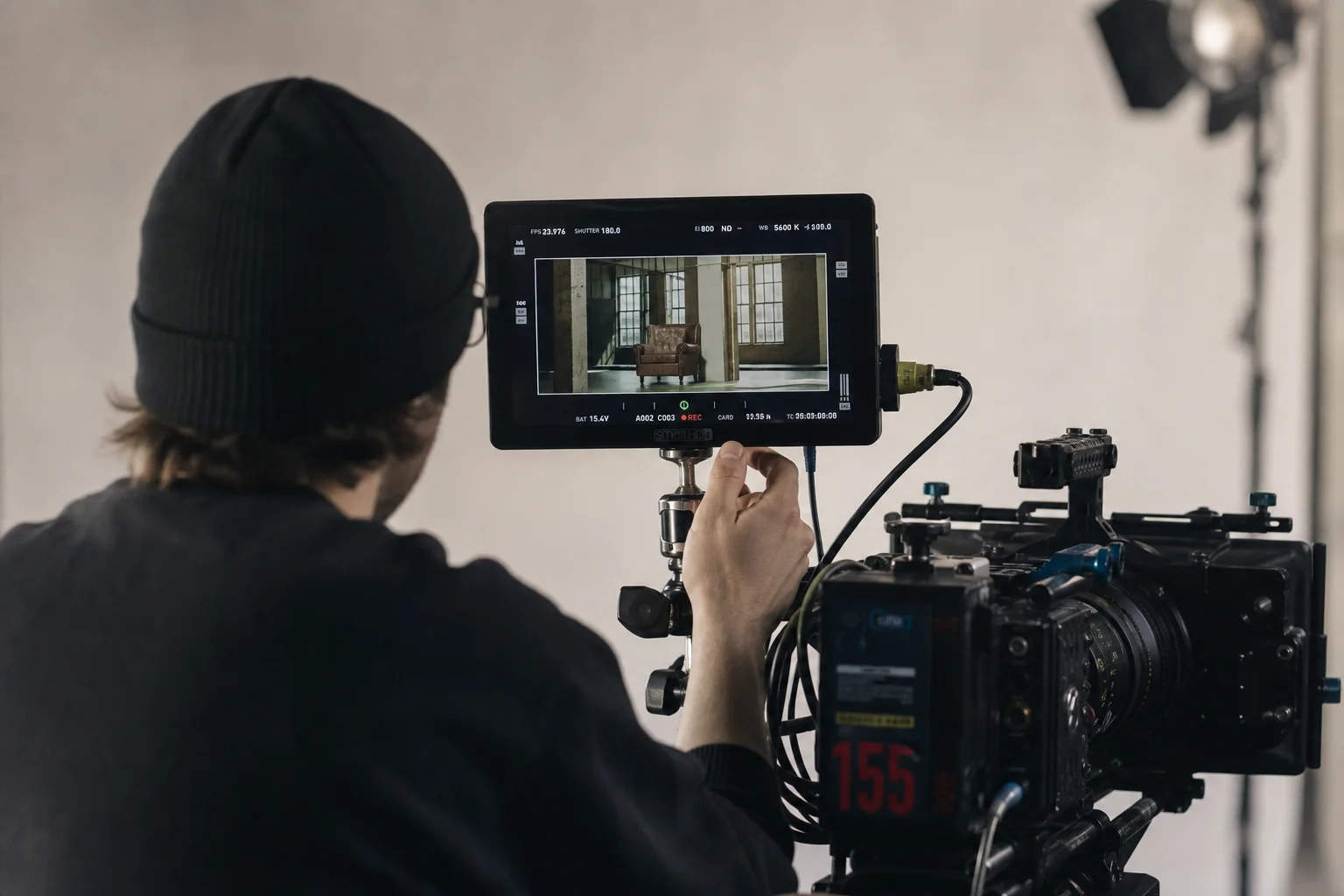 Videographer reviewing footage on external monitor while operating cinema camera in studio