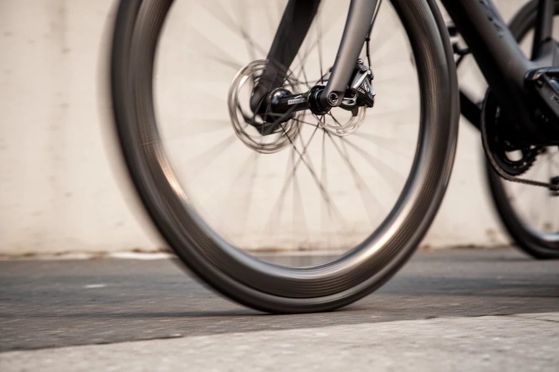 Primo piano di una ruota in carbonio a profilo alto che gira su una bici in movimento con raggi mossi