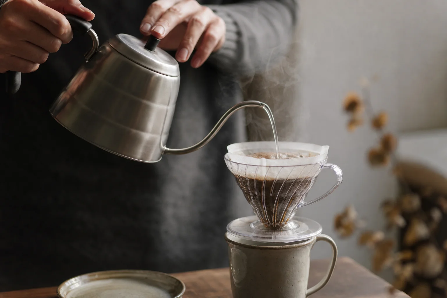 Hands pouring hot water from gooseneck kettle into V60 dripper