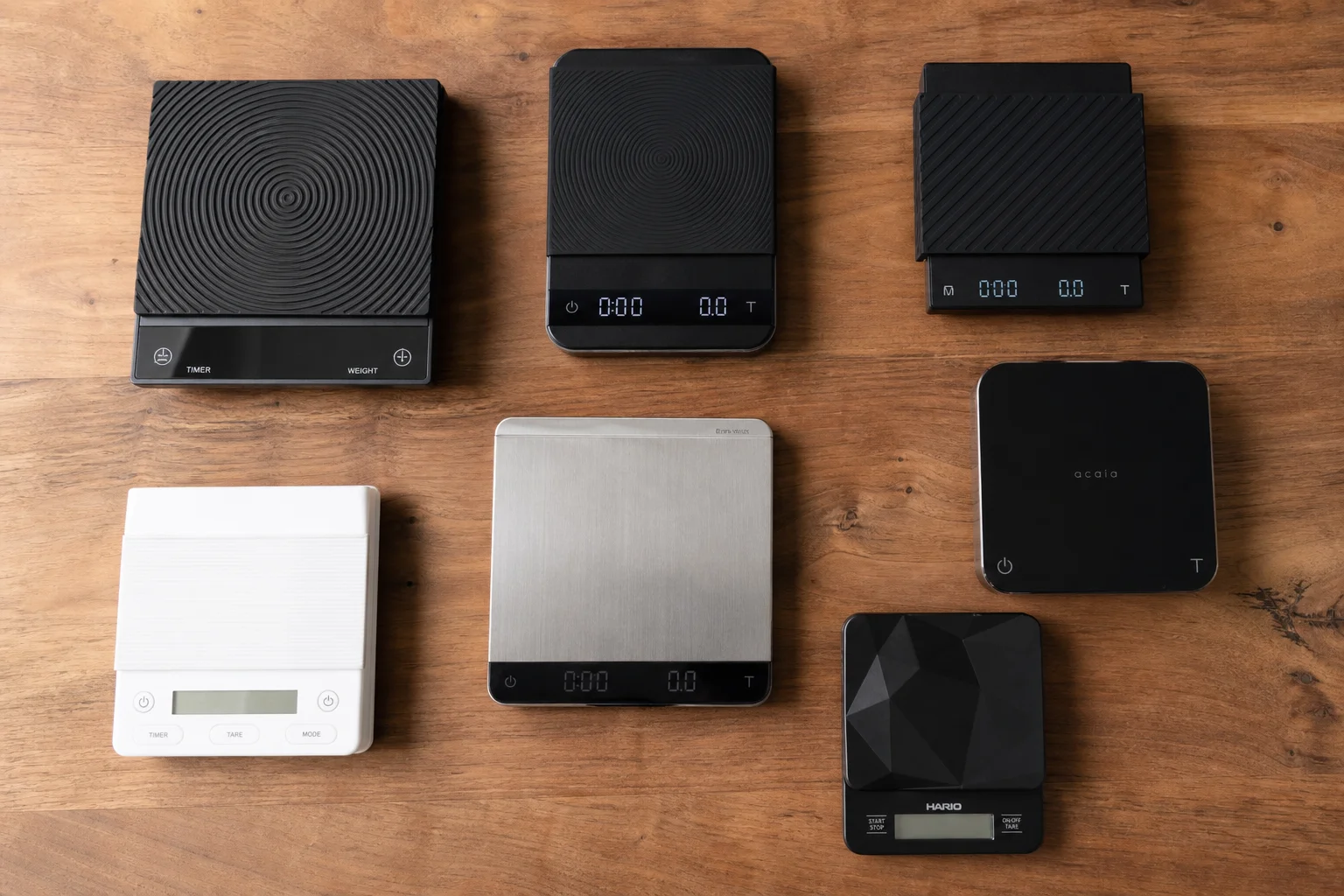 Overhead flat-lay of multiple coffee scales arranged on a wooden surface