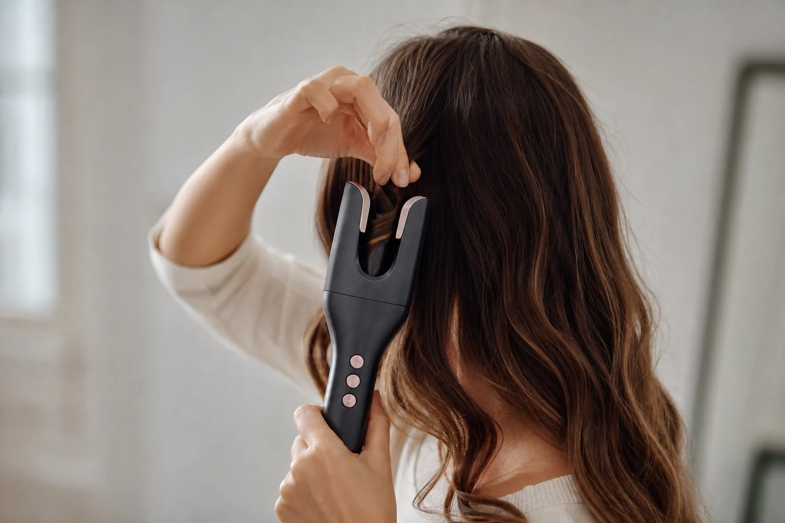 Donna che acconcia i capelli con un arricciacapelli automatico, concentrata sulla tecnica e sul posizionamento