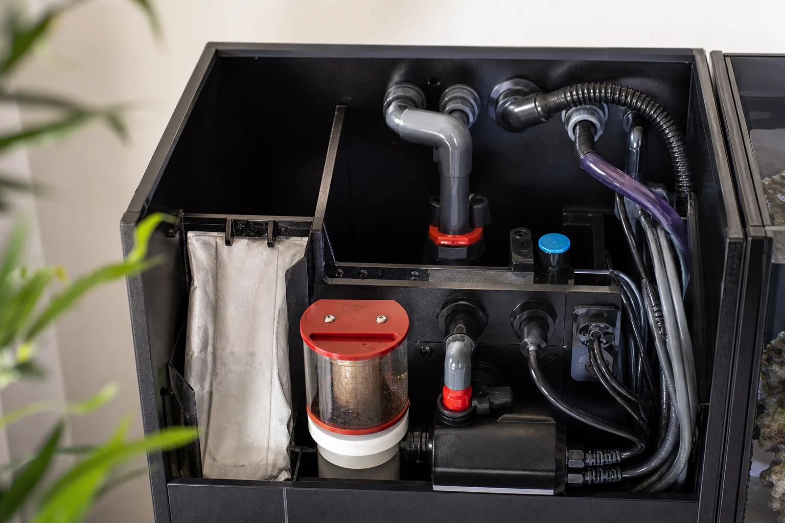 Compact aquarium overflow compartment with plumbing and equipment visible