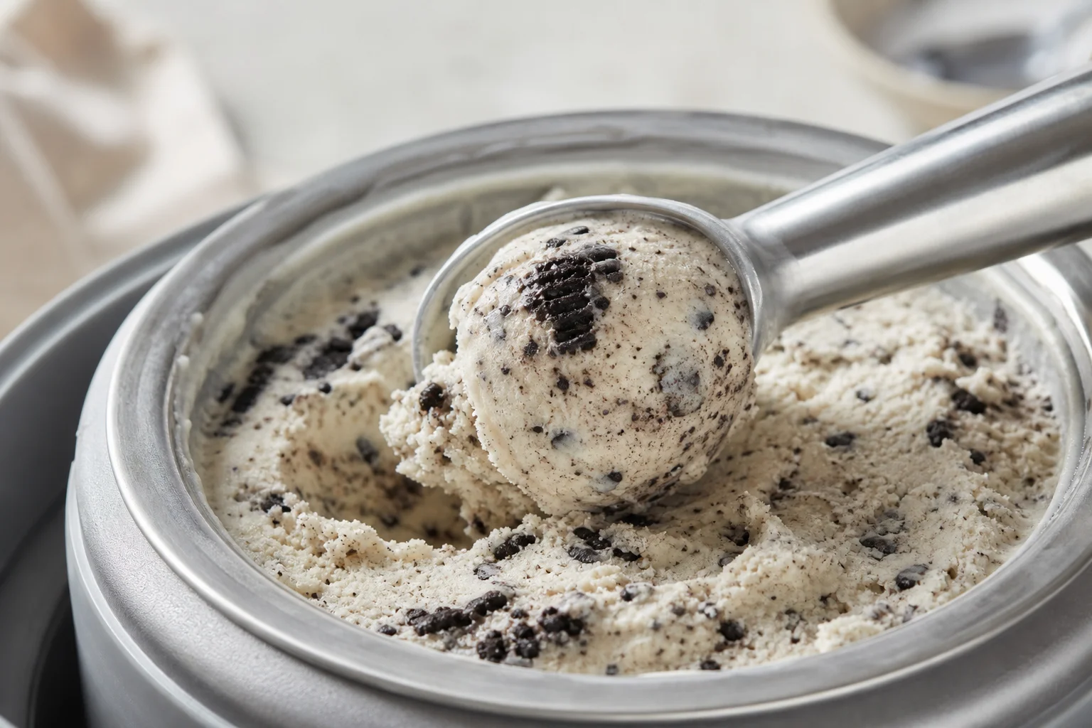 Ice cream scoop removing vanilla ice cream with Oreo pieces from bowl