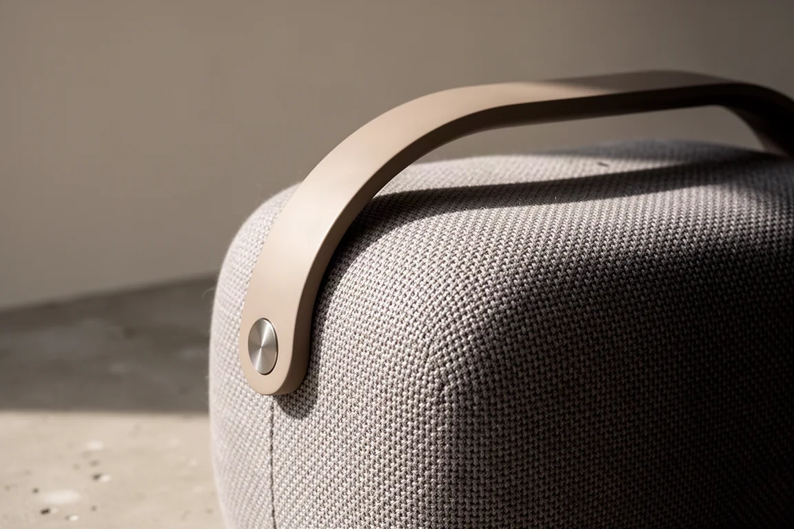 Close-up van geweven textieloppervlak van speaker met een gladde hendel die over de bovenkant buigt