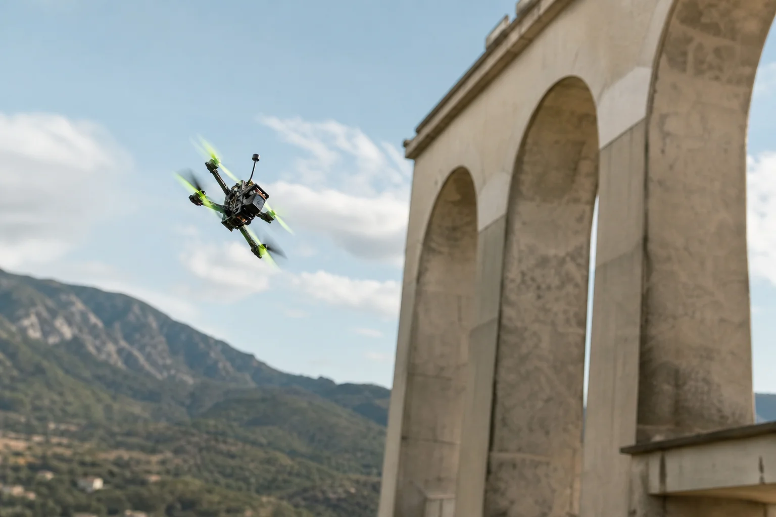 FPV drone performing aerial maneuver near outdoor landscape features