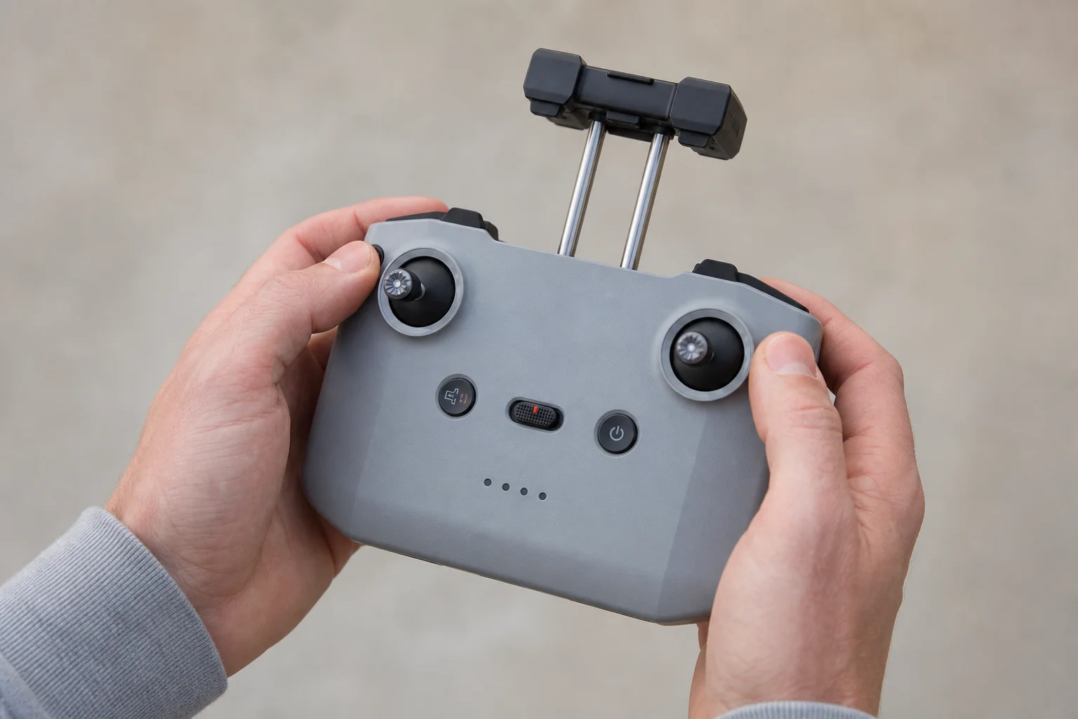 雙手持握 DJI Mini 4K 遙控器，展示按鍵配置與手機夾具