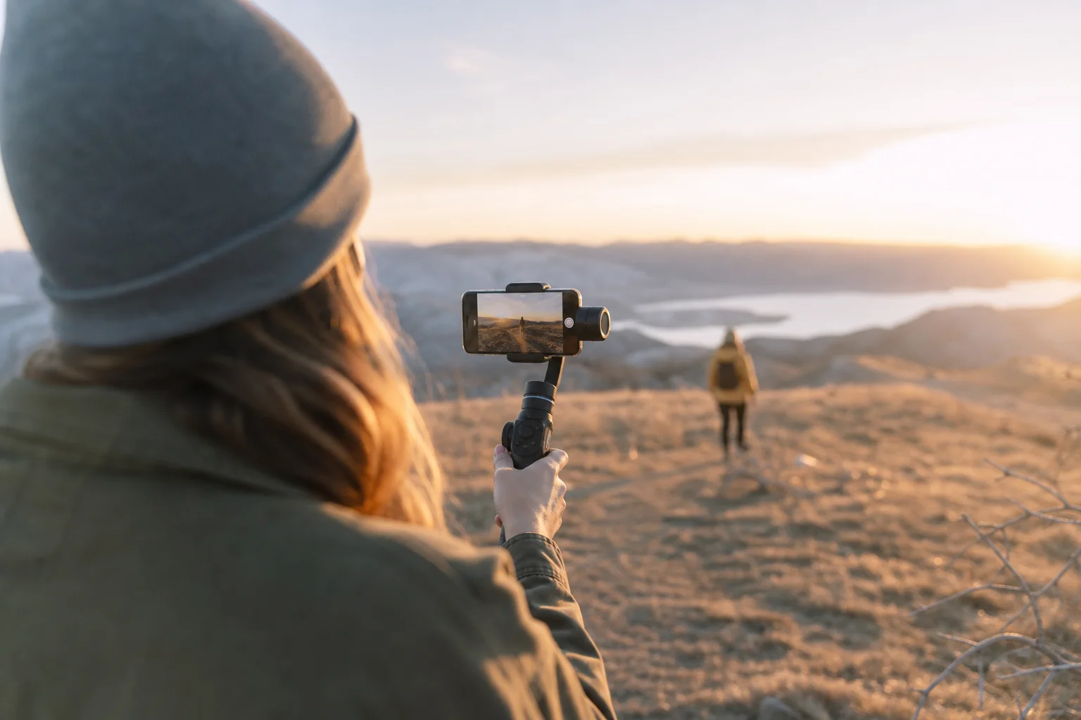 Content creator holding smartphone gimbal while filming outdoors in natural light