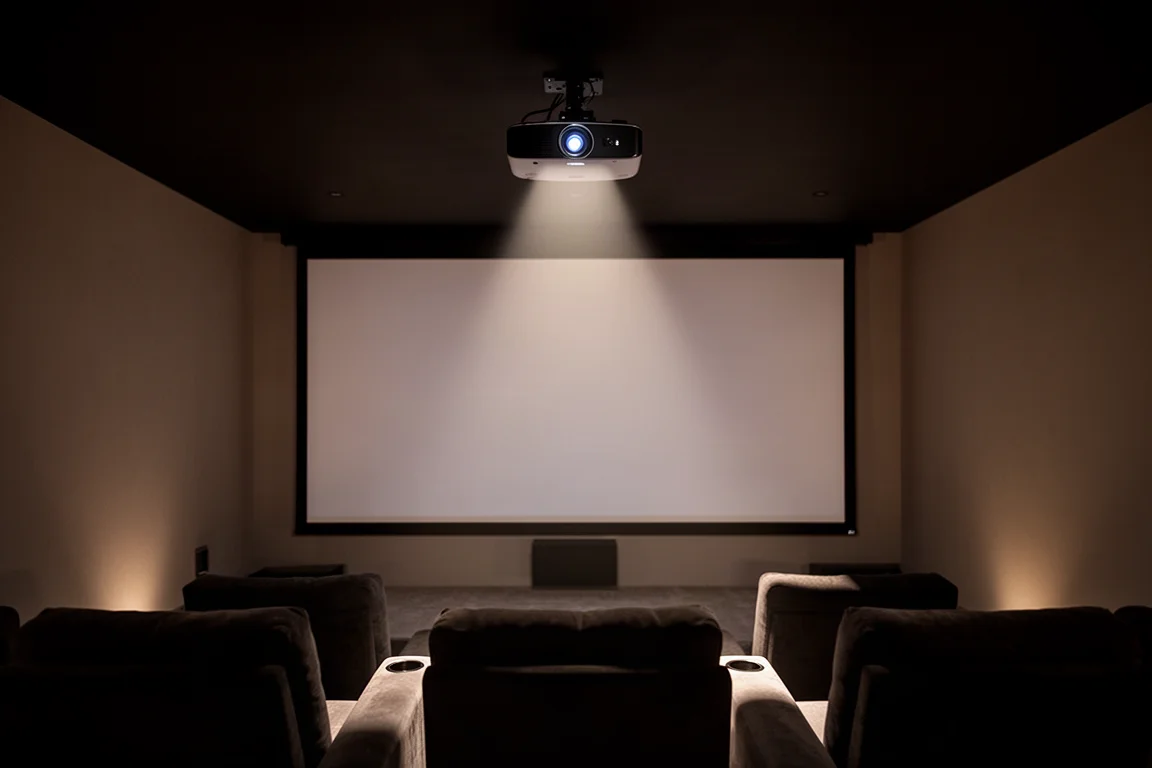 Projecteur monté au plafond dans une salle de home cinéma sombre, dirigé vers un écran de projection