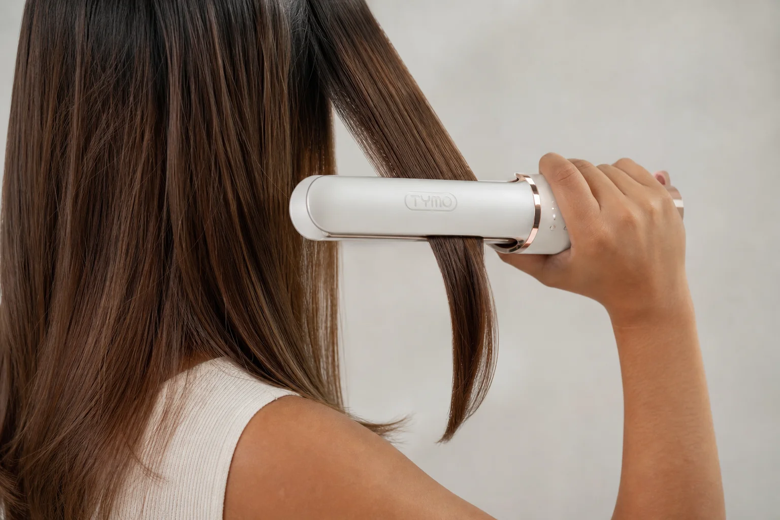 Hair stylist using a cordless straightener on a section of hair