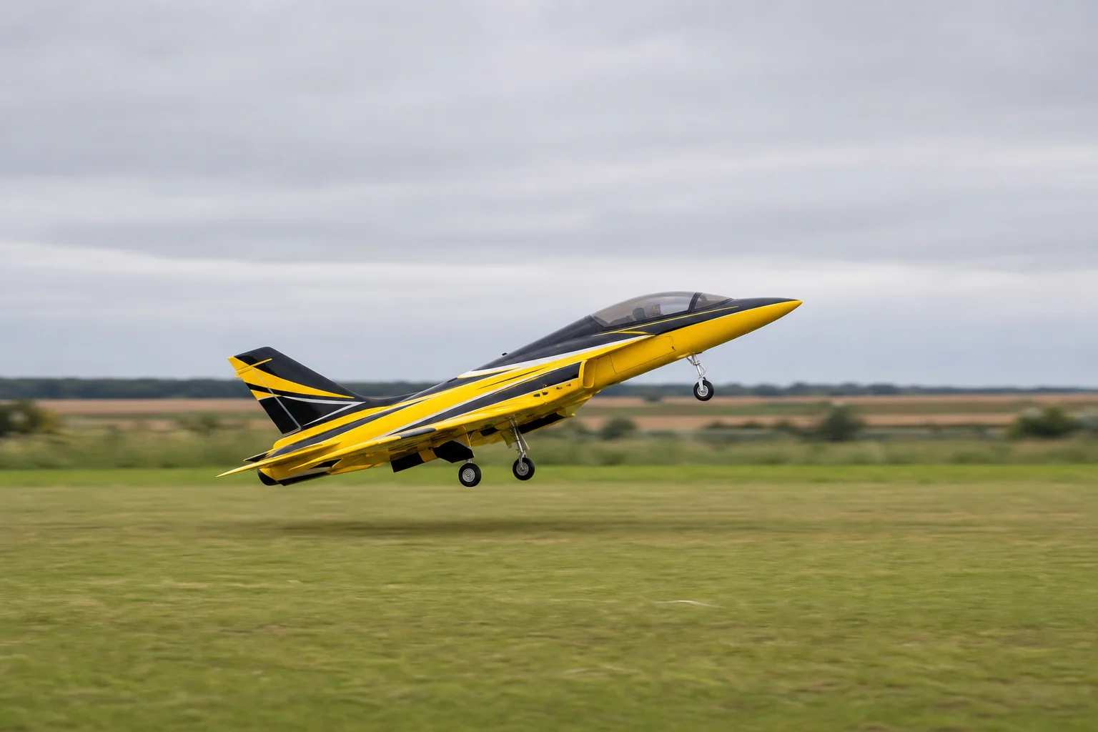 Jet RC despegando de un campo de hierba con el morro levantado