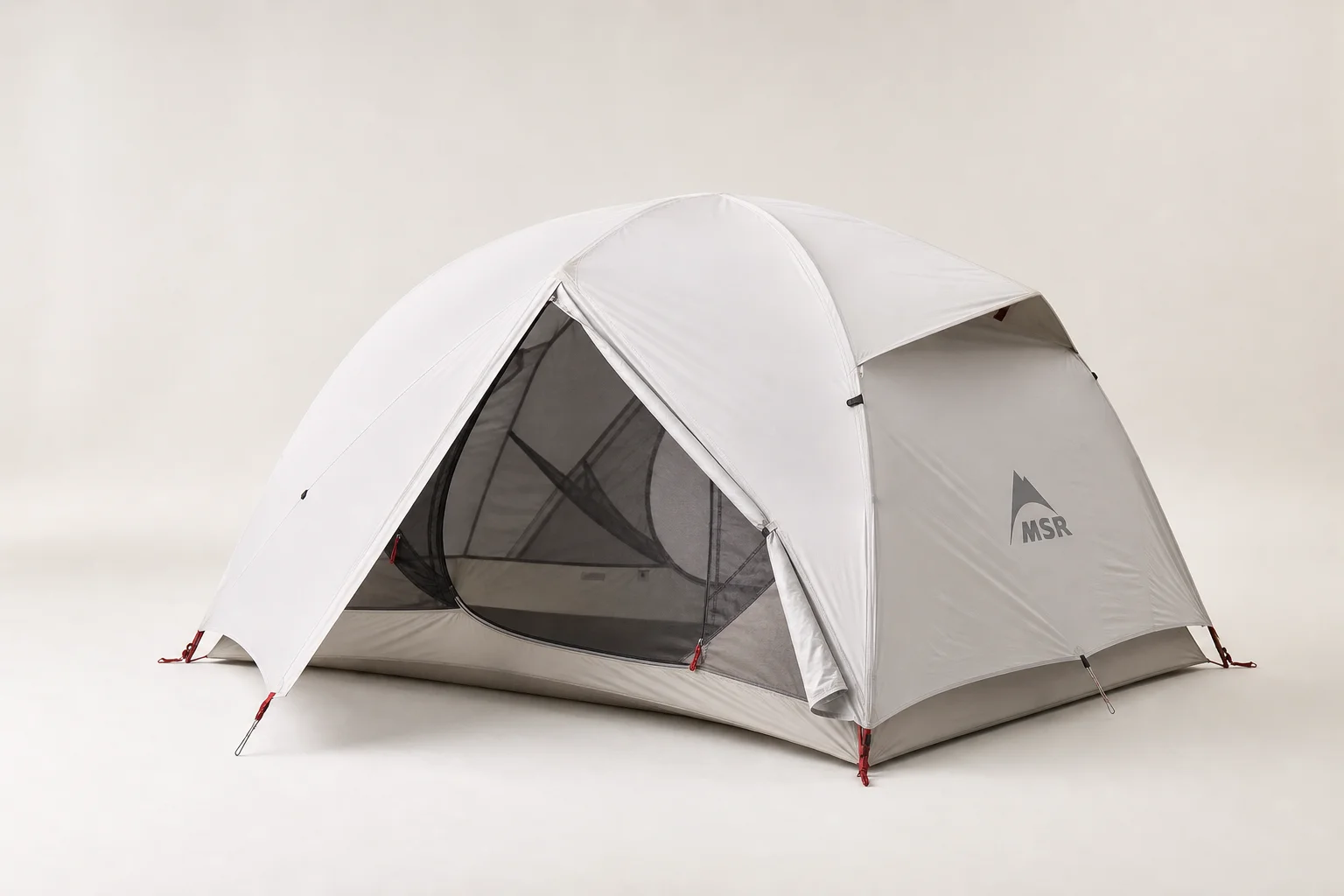 Equipo de moto camping que incluye tienda, saco de dormir, sierra, linterna frontal y filtro de agua sobre hormigón