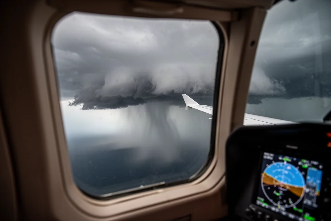 Weather radar display and storm cells visible through a side cockpit window