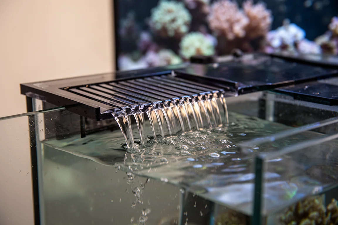 Nahaufnahme von Wasser, das über die geschlitzten Zähne eines Überlaufwehrs fließt