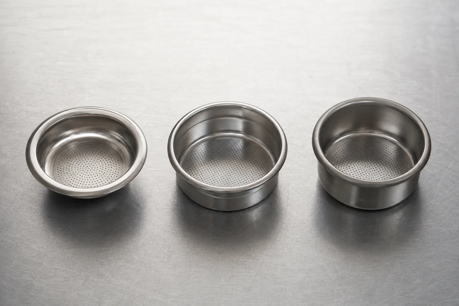 Three different espresso baskets arranged to show shape and size variations