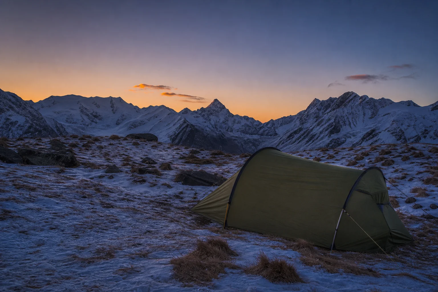 Tienda de campaña tipo túnel montada en un campamento alpino de gran altitud al atardecer