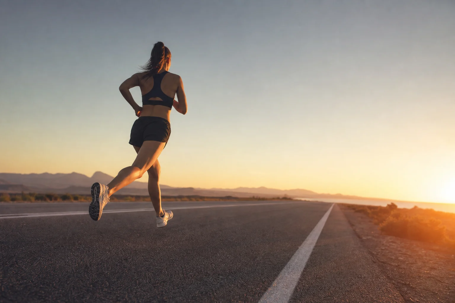 Marathon runner in stride on open road with early morning light