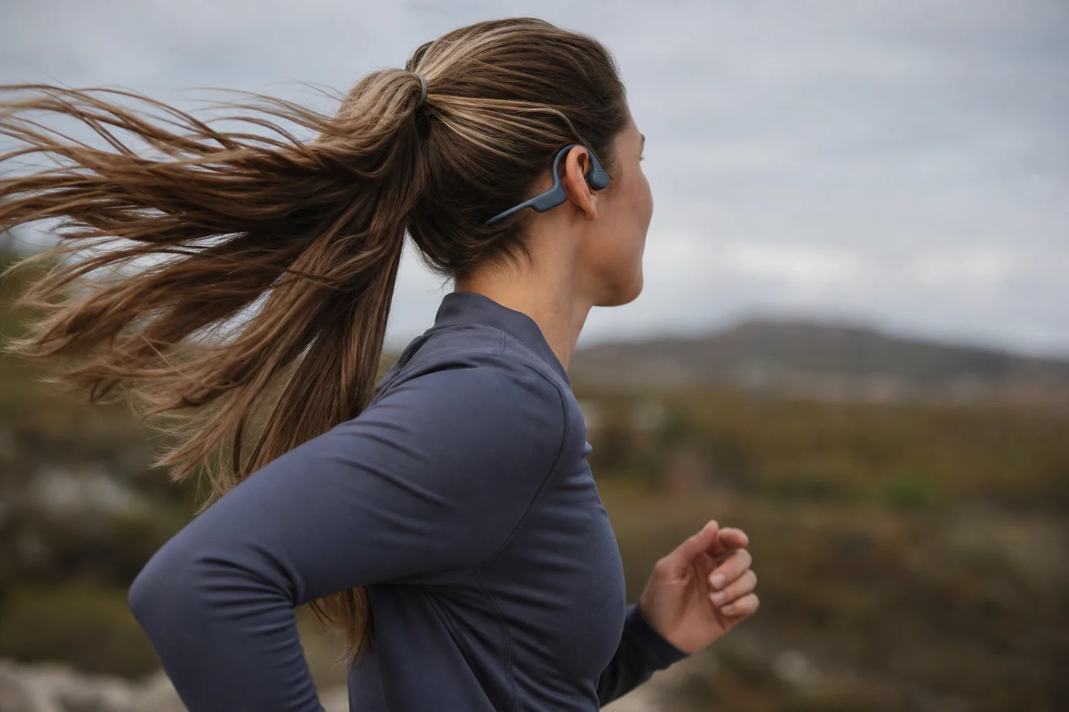 Runner wearing open-ear bone conduction earbuds during outdoor training