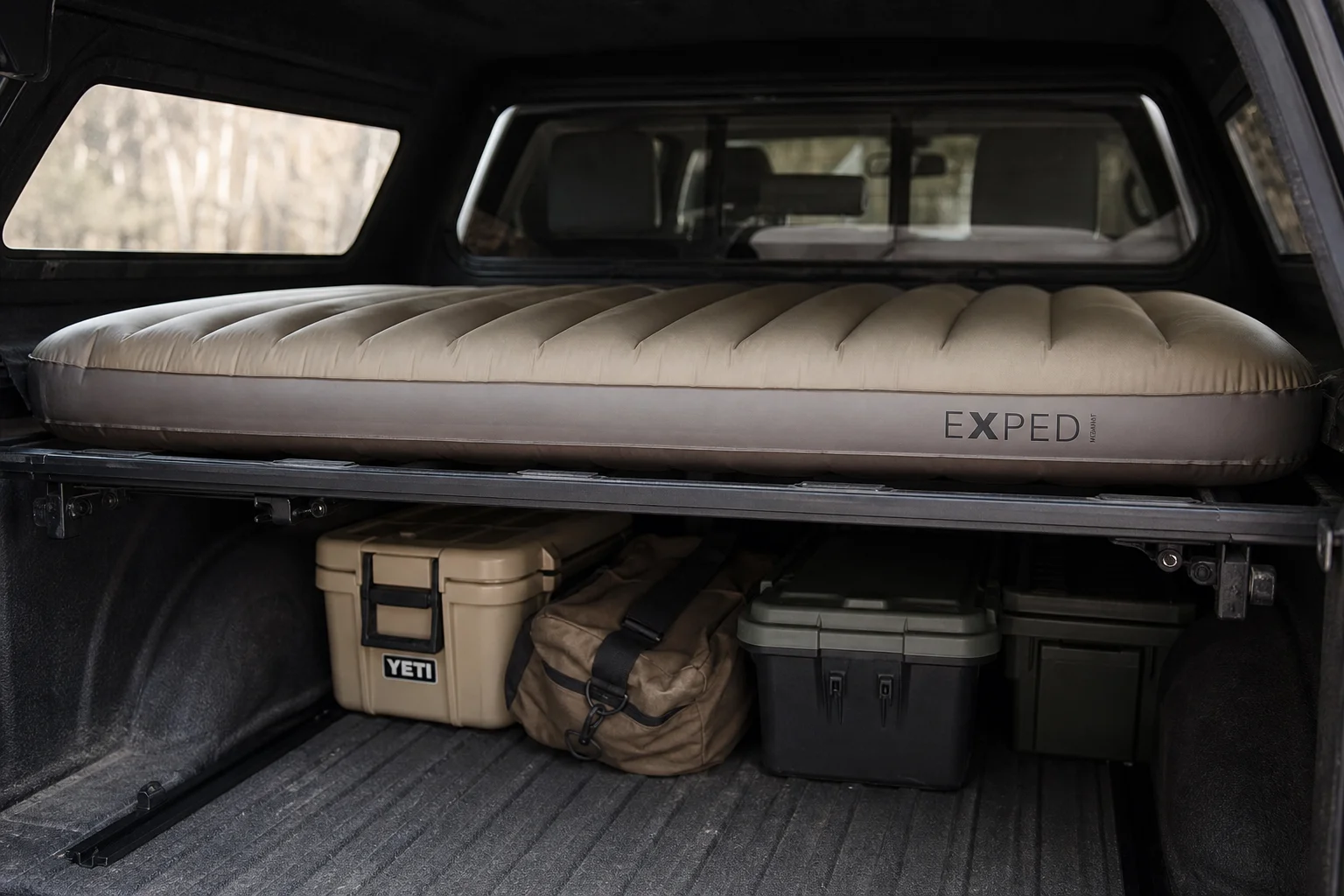 Camping mattress laid out in a truck bed with storage space visible underneath